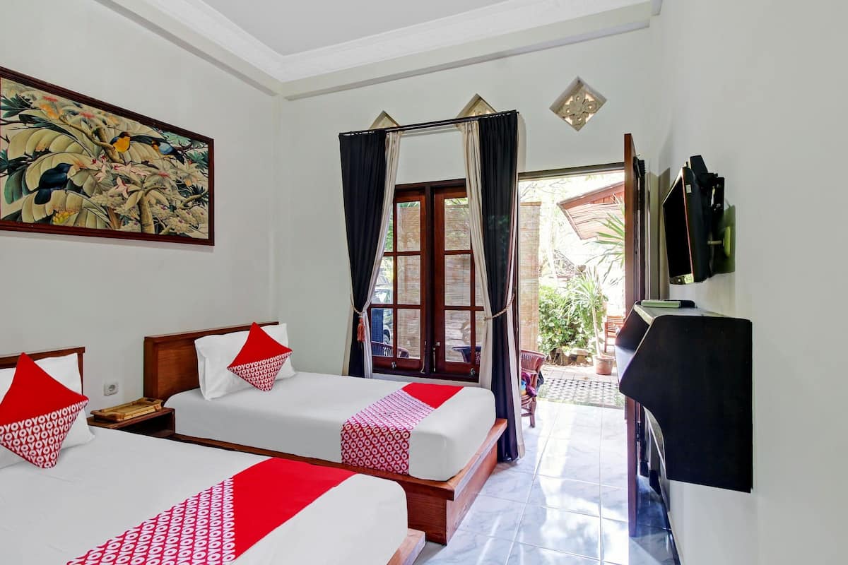 A hotel room with two beds, a large painting, a television, and a view of the outside.