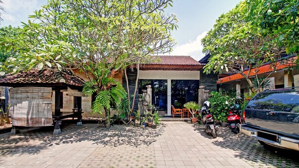 A courtyard with a tiled floor, a small structure, and a parked car.