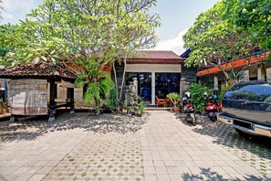 A courtyard with a tiled floor, a small structure, and a parked car. - Super OYO 90672 ADHYA GUEST HOUSE LOMBOK (Mataram)