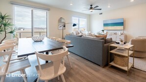 Un salon moderne comprenant un coin repas, un canapé gris et un ventilateur de plafond.