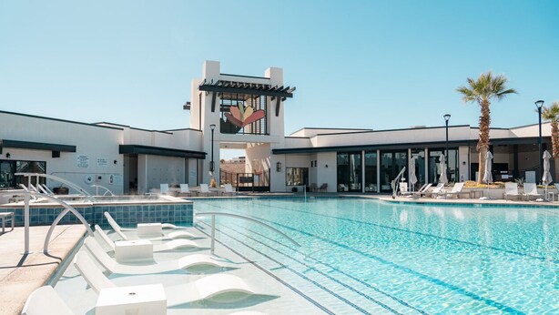 Un hôtel moderne doté d’une piscine, de chaises longues et de palmiers.