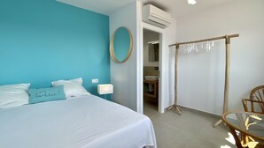 Un dormitorio con cama, mesita de noche, aire acondicionado de pared y un tendedero de madera.