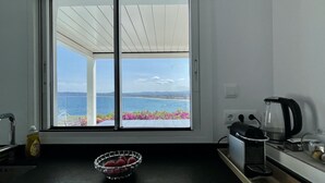 Una cocina con vista al mar, una cafetera y un frutero sobre la encimera.