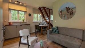 Ein modernes Wohnzimmer mit einer Couch, einem Esstisch und einer Küchenzeile mit einer Treppe.