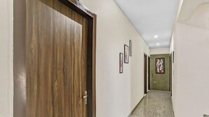 A hallway with a wooden door, framed pictures on the walls, and a staircase leading to another room. - Hotel Noida Continental  (Noida)