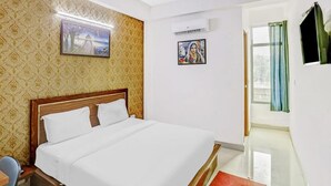 A hotel room with a bed, a ceiling fan, a wall-mounted air conditioner, and a window with curtains. - Hotel Noida Continental  (Noida)