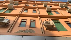 A building facade with multiple air conditioning units, rectangular windows, and a tiled lower section. - Hotel Noida Continental  (Noida)