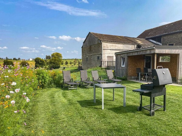 A grassy outdoor area with lounge chairs and a barbecue grill.