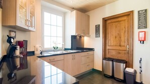 A modern kitchen with a large window, stainless steel appliances, and wooden cabinets. - Pretty Farmhouse in Houffalize with Courtyard (Houffalize)