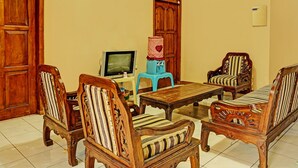 A traditional living room with wooden furniture, a television, and a clock on the wall.