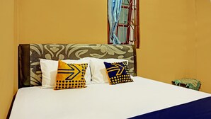 A bed with patterned pillows and a blue and yellow blanket.