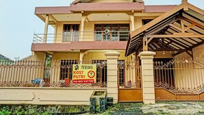 A two-story house with a balcony, a sign advertising a house for sale, and a gated entrance.