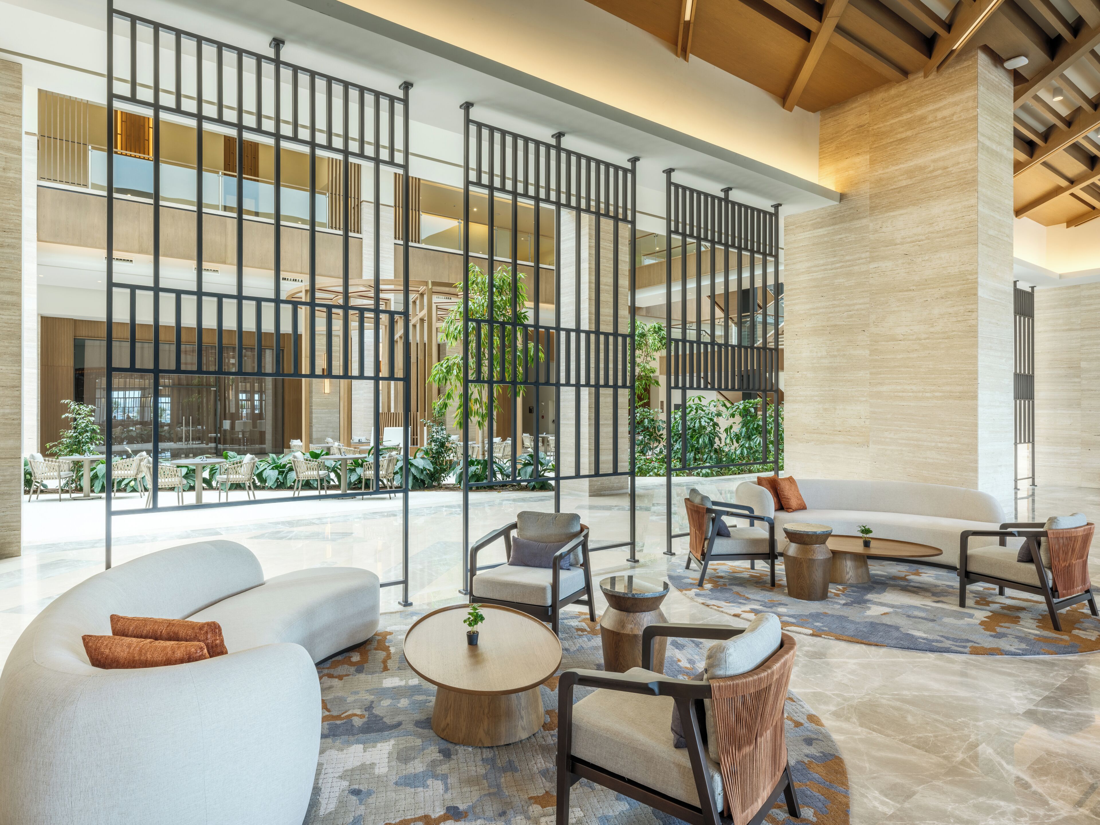 A spacious lobby with modern furniture, a central seating area, and large windows overlooking a courtyard.