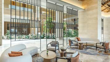 A spacious lobby with modern furniture, a central seating area, and large windows overlooking a courtyard.