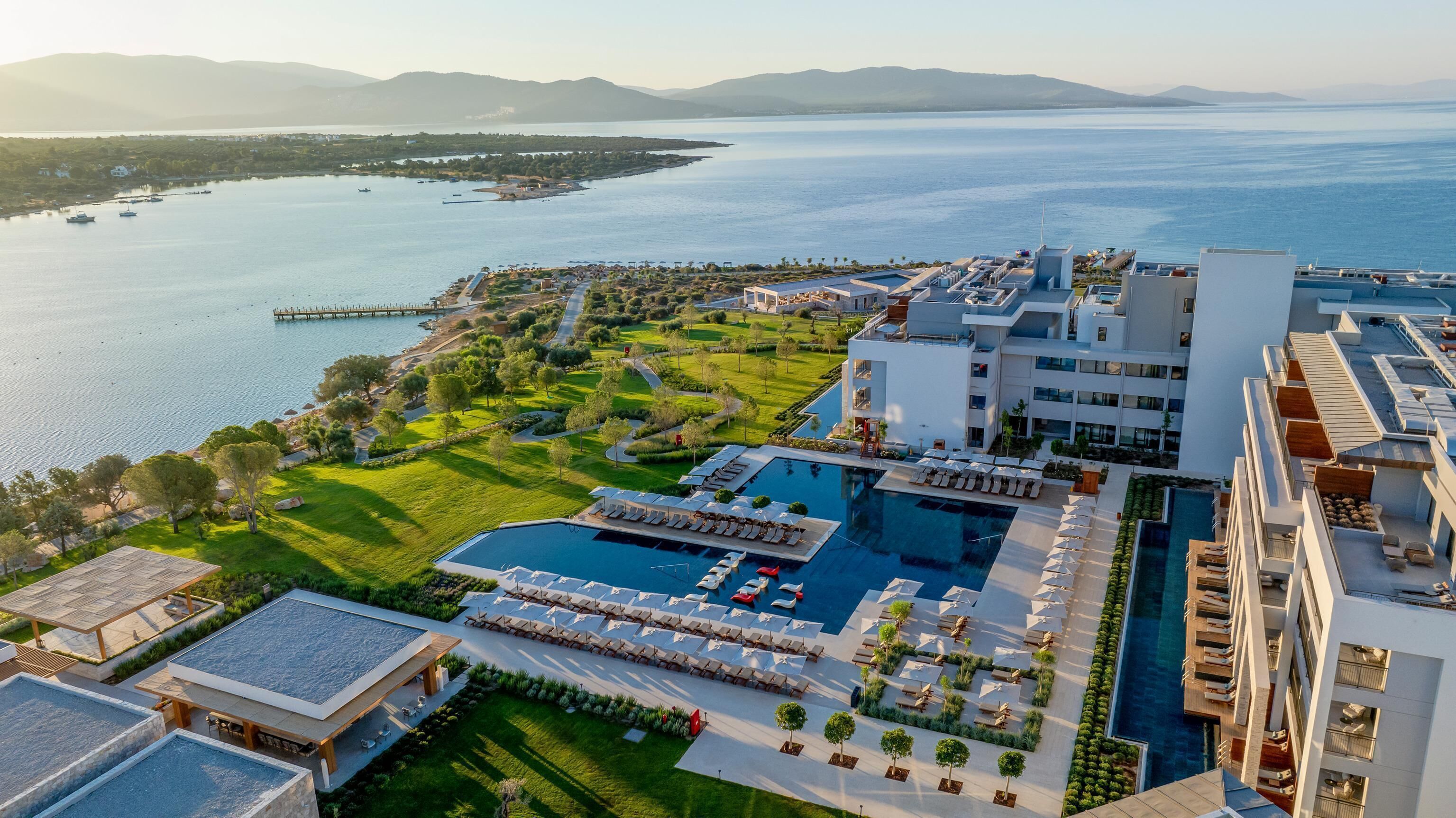 Un resort con una piscina grande, tumbonas y vista al mar.