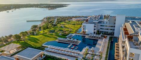 Un resort con una piscina grande, tumbonas y vista al mar.