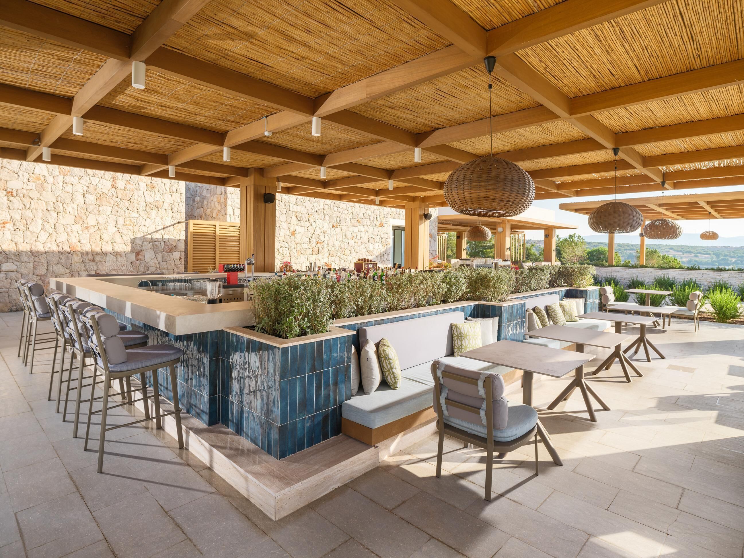 Un espace bar extérieur avec des murs en pierre, une piscine et des sièges en plein air.