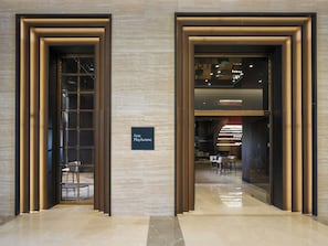 Enter a sleek, minimalist space with a welcoming gateway and a contemporary interior featuring a seating area with tables and chairs.