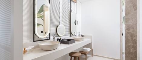 Une salle de bain moderne avec deux lavabos, de grands miroirs et un banc en bois.