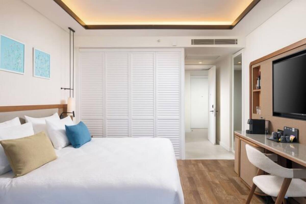 A hotel room with a bed, a desk, a TV, and a wardrobe.