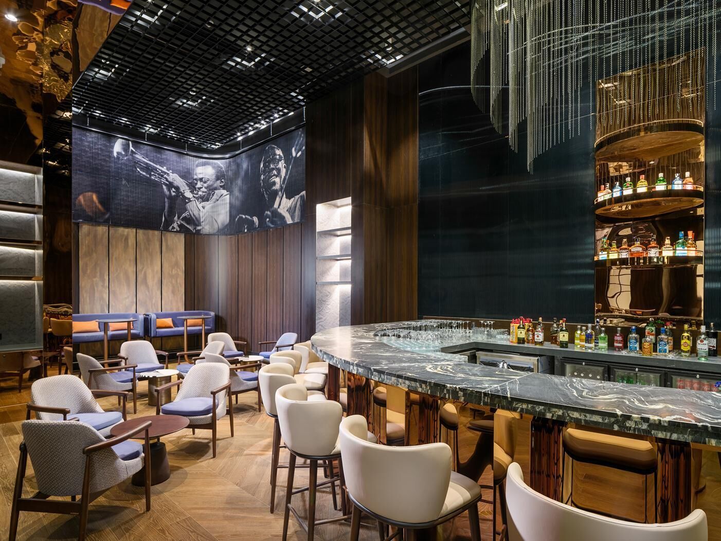 A bar area with seating, a large screen, and a bar counter with bottles.