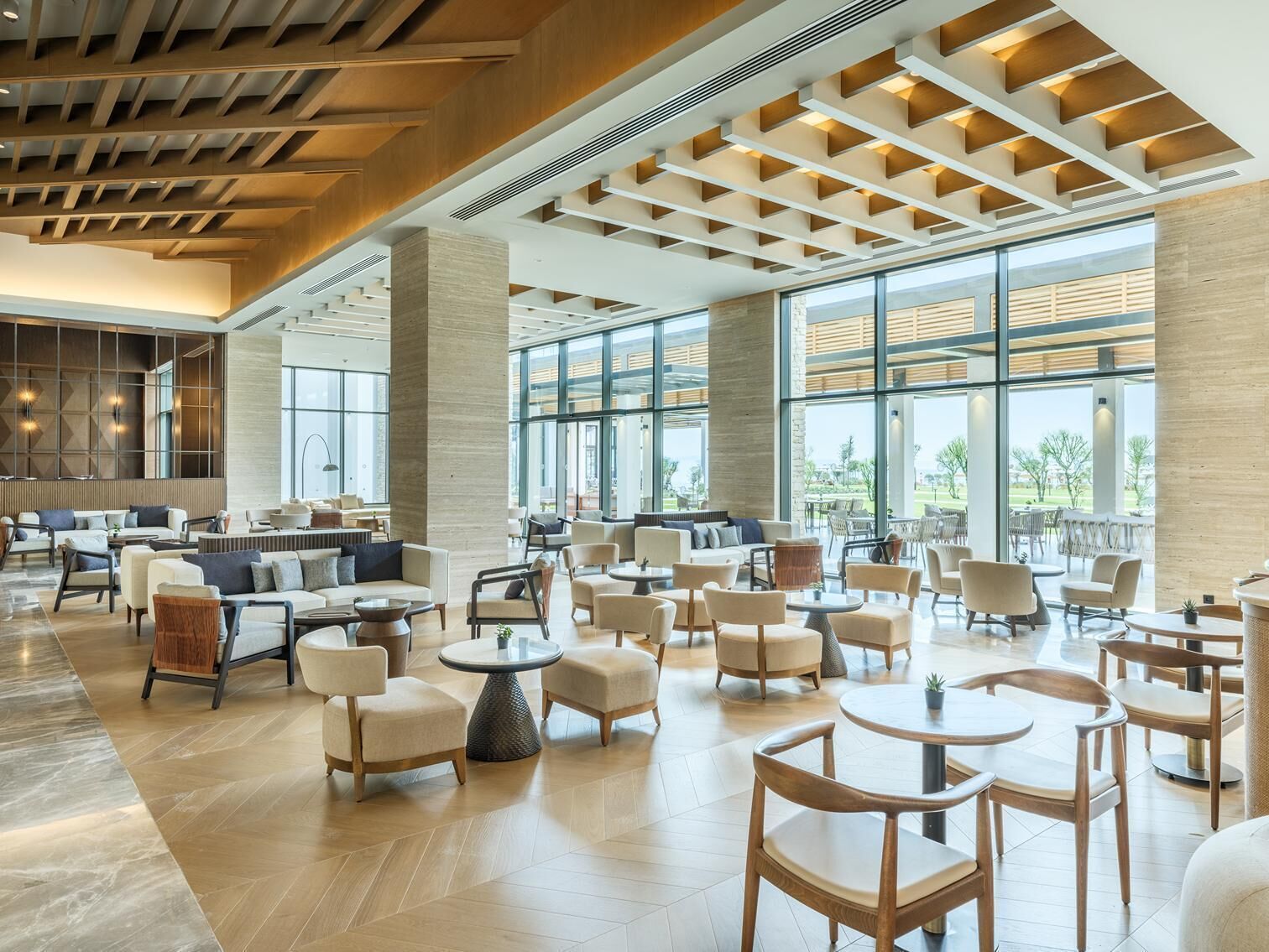 A spacious indoor area with multiple seating arrangements, large windows, and a modern architectural design.