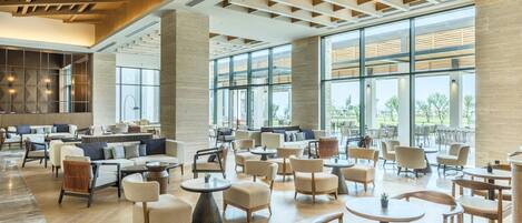 A spacious indoor area with multiple seating arrangements, large windows, and a modern architectural design.
