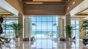 A spacious lobby with a large glass wall offering a view of the sea and buildings. - Anda Barut Collection - Ultra All Inclusive (Didim)