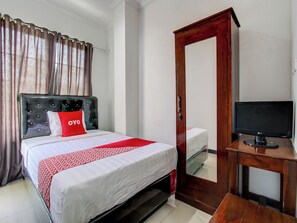 A hotel room with a bed, a TV, and a wardrobe. - OYO 92479 Pasadena House (Semarang)