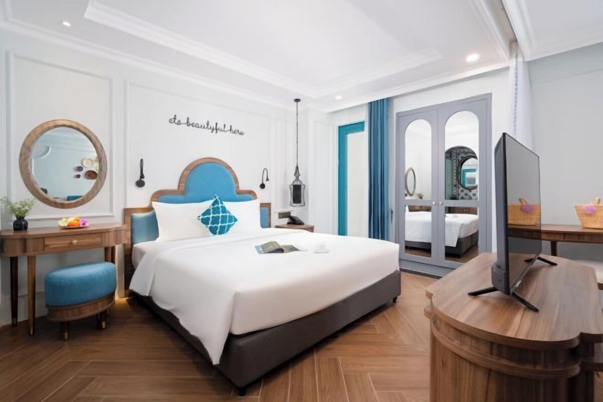 Una habitación de hotel moderna con una cama grande, un escritorio, un espejo y un televisor.