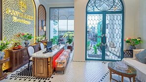 Un moderno vestíbulo de hotel con mostrador de recepción, zona de estar y un amplio ventanal arqueado con vistas al exterior.