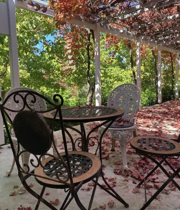 An outdoor patio with a pergola, covered seating, and a table.