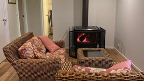 Una sala de estar acogedora con muebles de mimbre, una chimenea y una puerta que da a otra habitación.