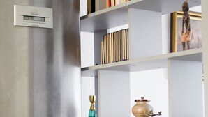 A modern kitchen with a stainless steel refrigerator, a built-in bookshelf with various items, and a coffee maker on the countertop. - Ulysses Apartments Acropolis (Athens)