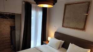 A neatly made bed with white linens, a wooden headboard, and a bedside table with a lamp. - Ulysses Apartments Acropolis (Athens)