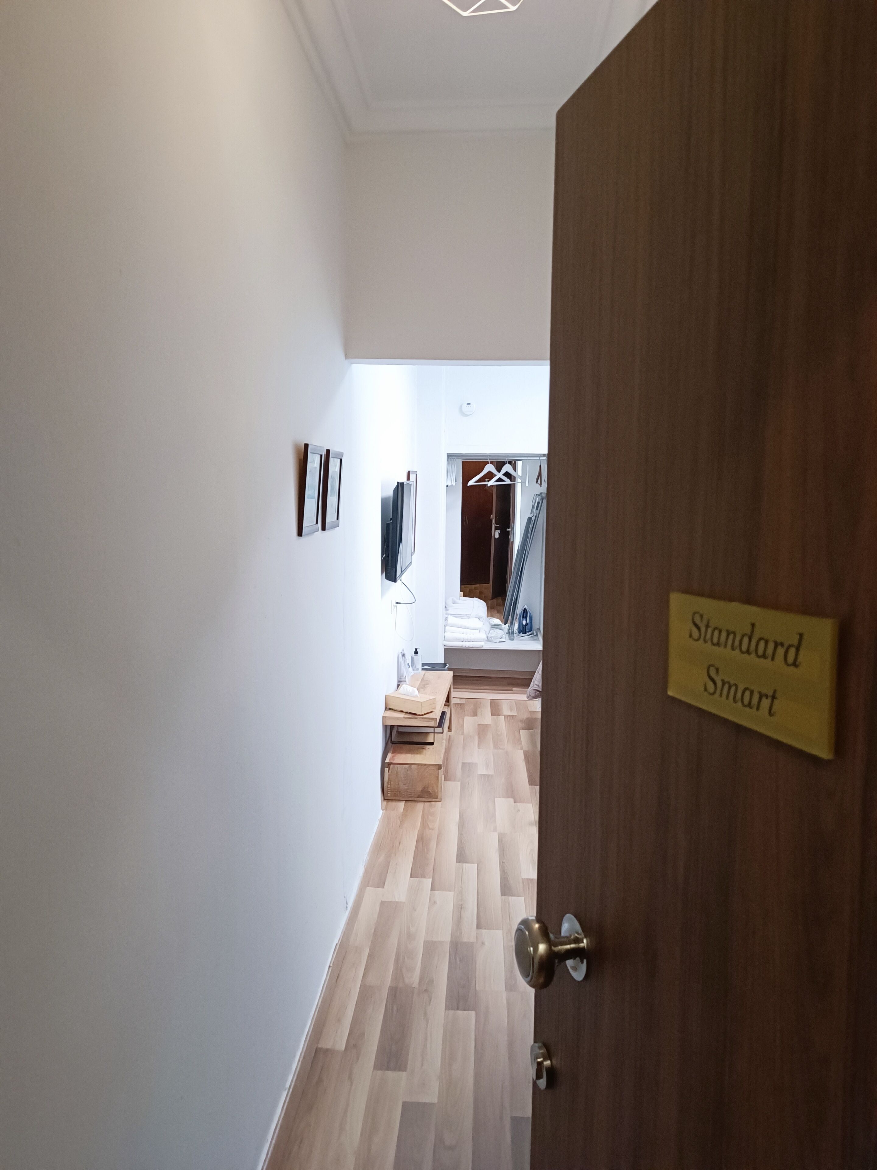 A hallway with a wooden door labeled "Standard Smart," a wooden bench, and a coat rack.