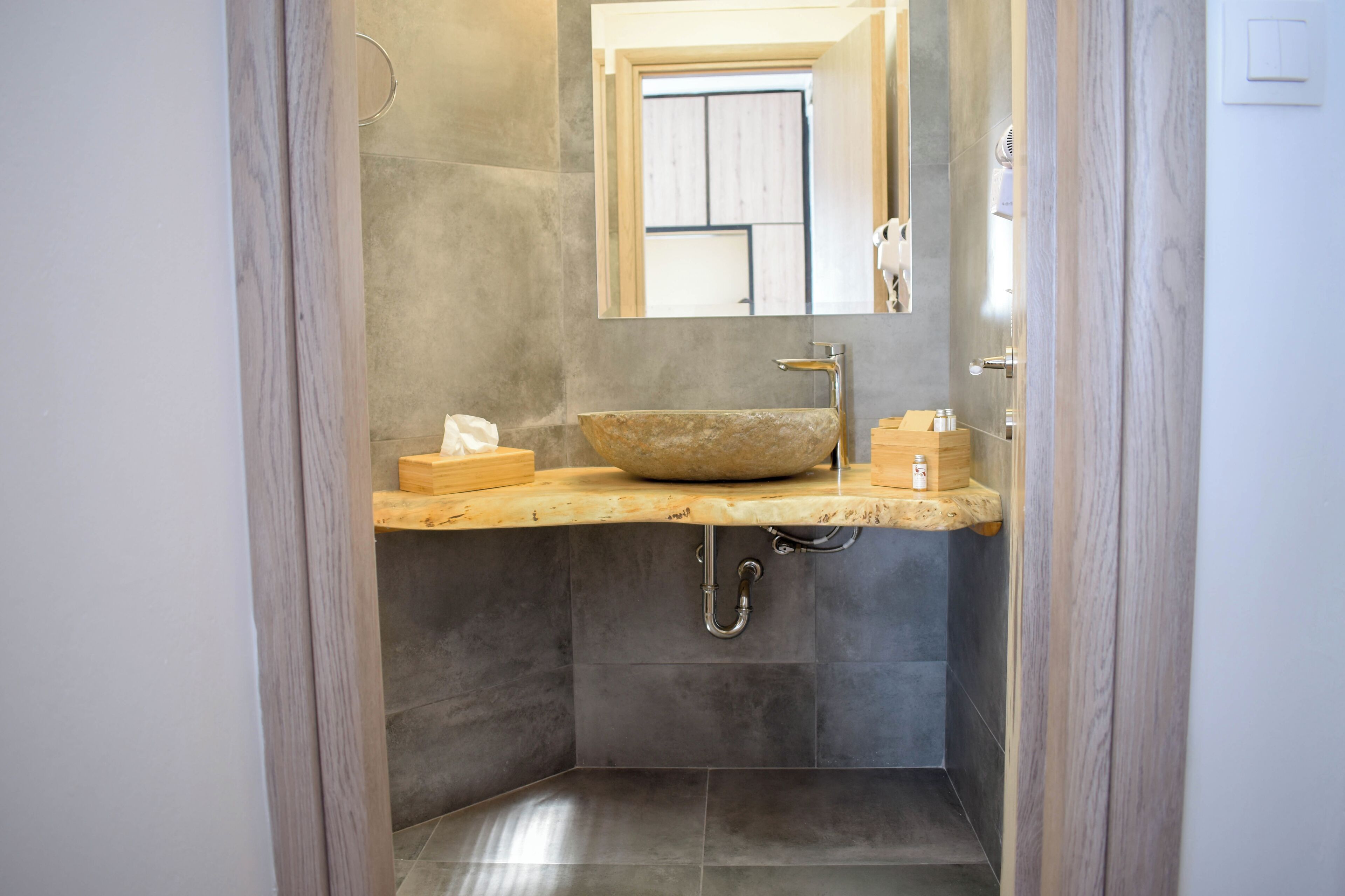 A bathroom with a stone sink, wooden countertop, and a mirror above it.