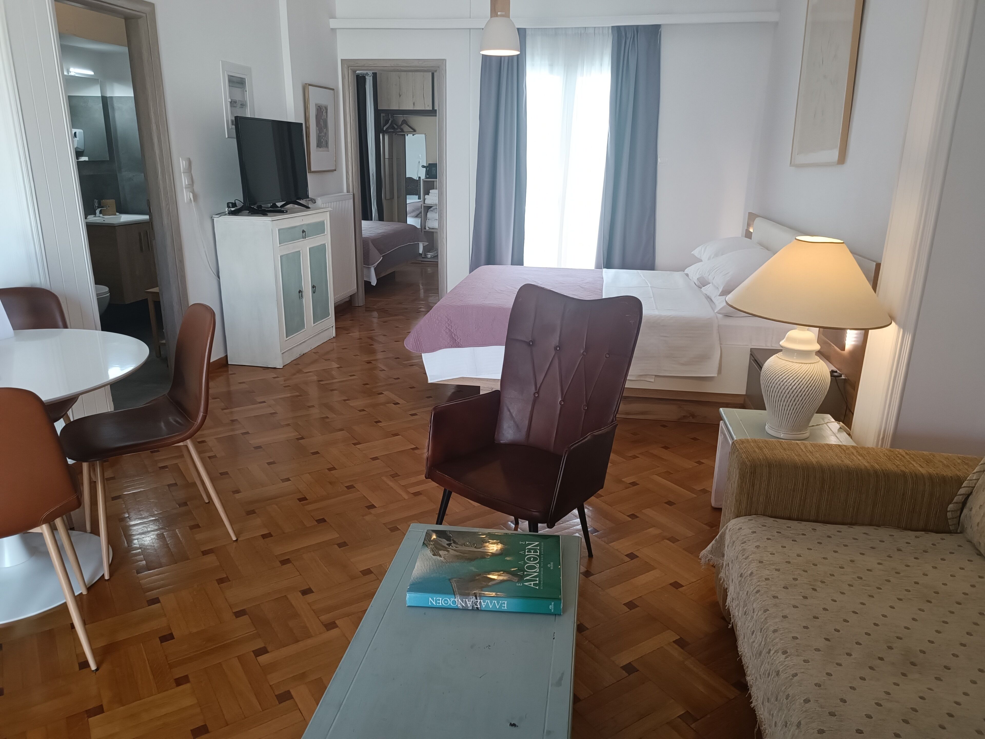 Een hotelkamer met een bed, bureau, stoel, tafel en lamp.