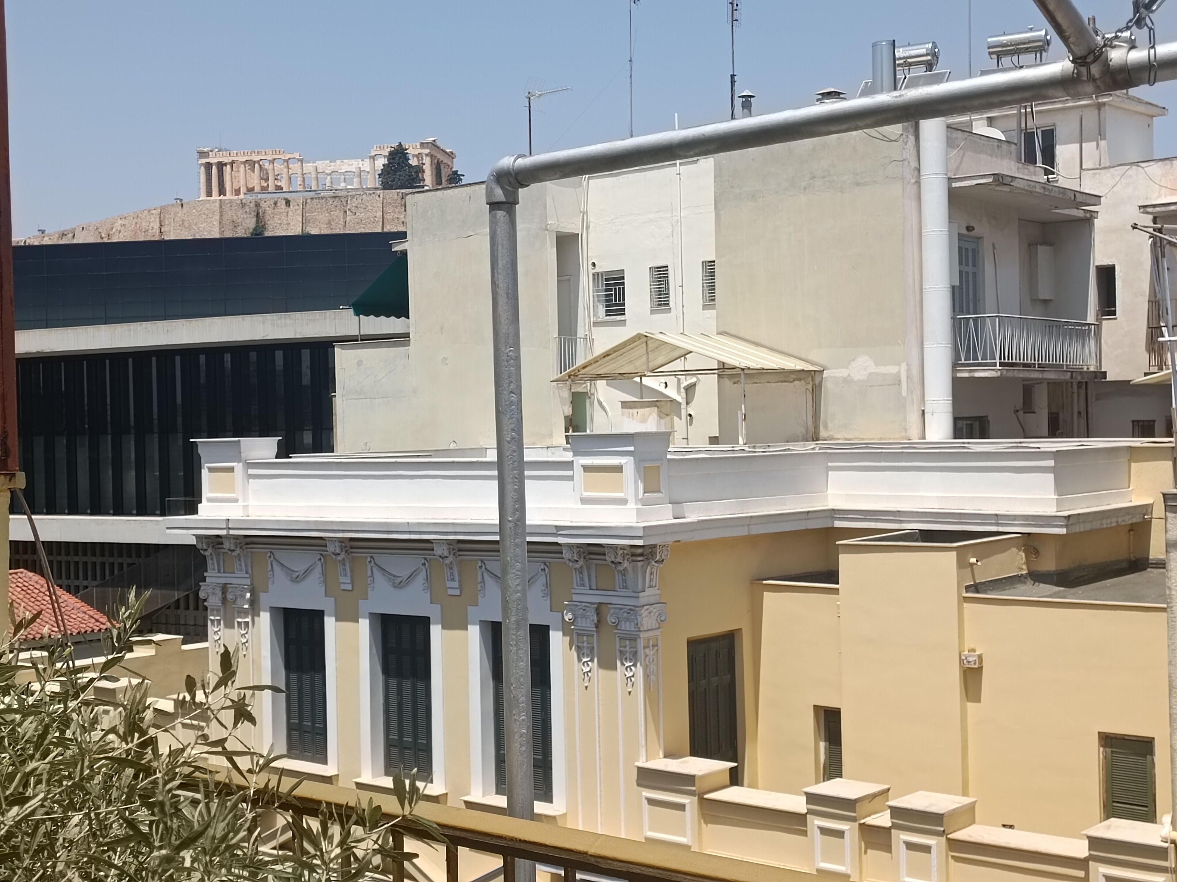 Un edificio con balcón, una ventana con contraventanas y barandilla blanca.