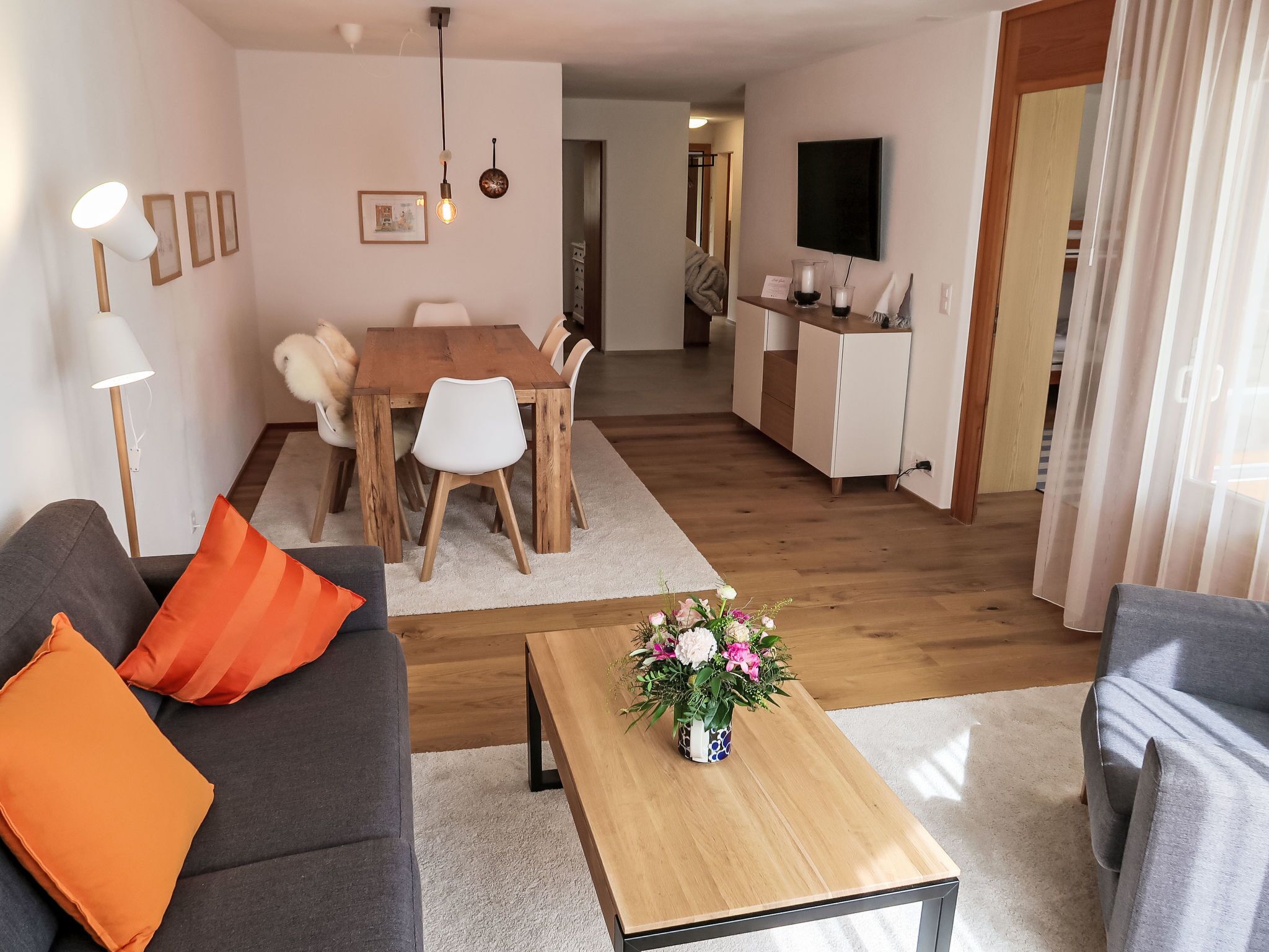 Ett modernt vardagsrum med en soffa, ett soffbord och en matplats med ett träbord och stolar.