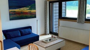 A living room with a blue sofa, a coffee table, and a painting of a landscape.