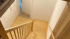 A wooden staircase leading to a room with white walls and a wooden floor.
