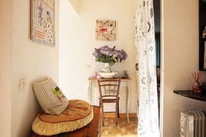 Une pièce avec un lit en bois, une chaise, un bureau orné d’un vase de fleurs et un radiateur.