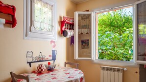 Un comedor con una mesa preparada para dos, una ventana con vistas a zonas verdes y un radiador debajo de la ventana.