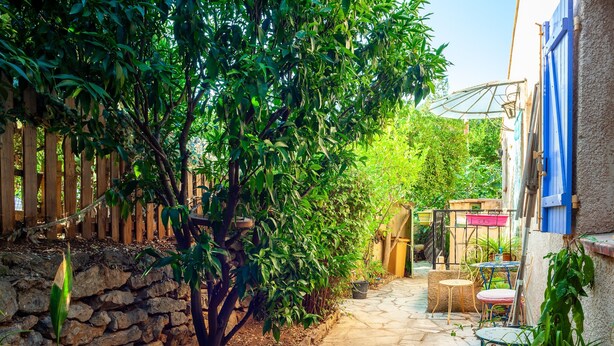 Un patio empedrado con cerramiento de madera, pared de piedra y plantas en macetas.