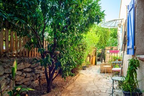 Un patio empedrado con cerramiento de madera, pared de piedra y plantas en macetas.