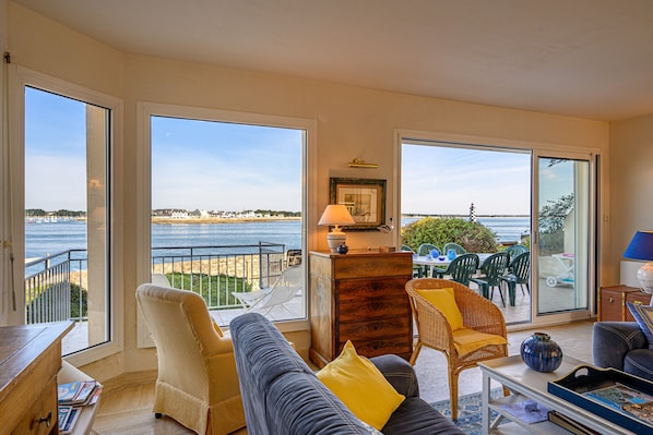 Un salon avec vue sur la mer, comprenant un canapé, des fauteuils, une table et un meuble en bois.