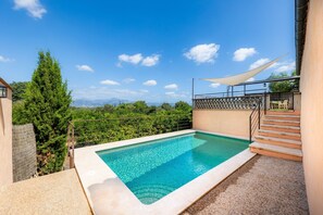 Una piscina con vistas a las montañas, una escalera y una zona con sombra.