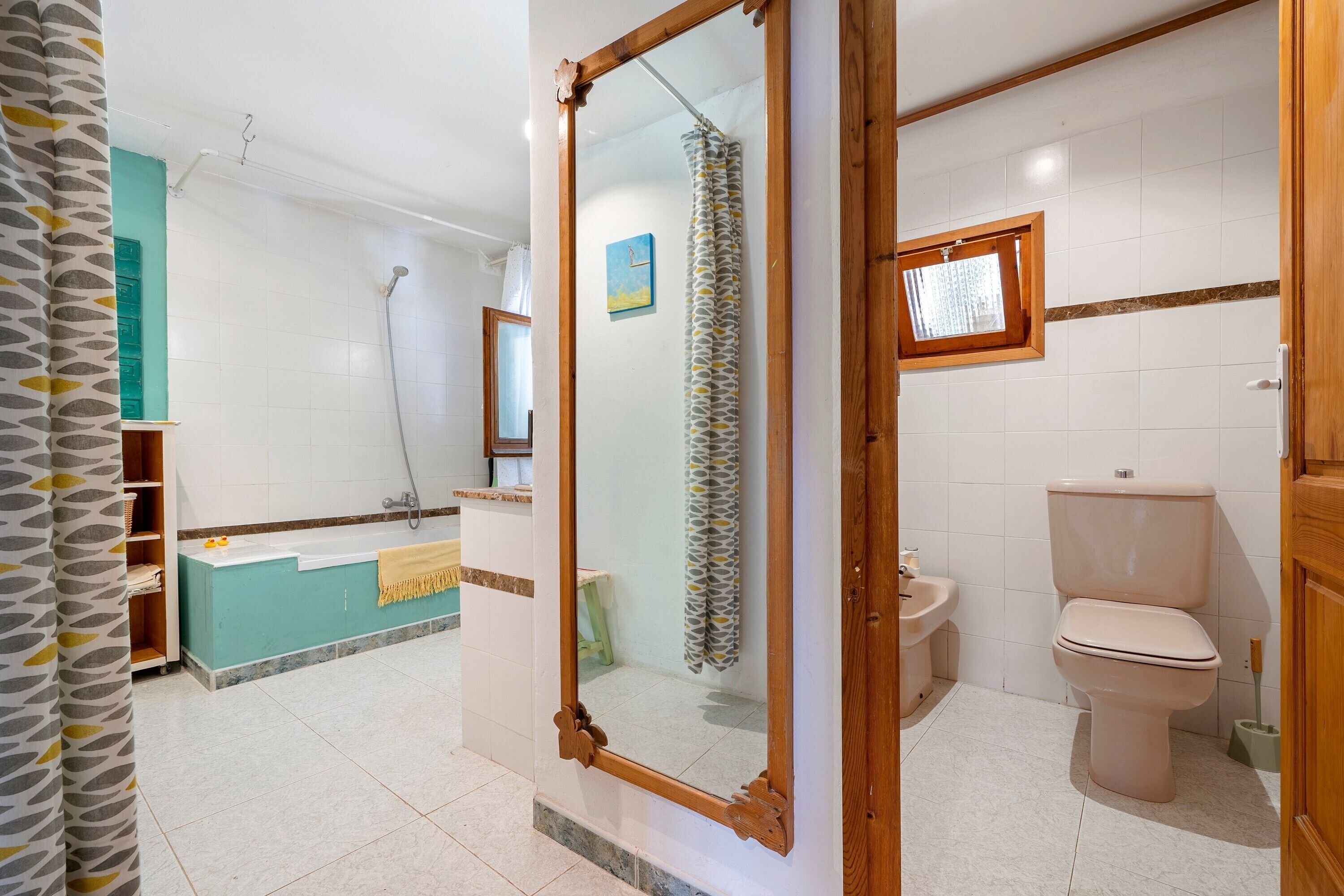 A bathroom with a shower, toilet, sink, and a mirror with a wooden frame.