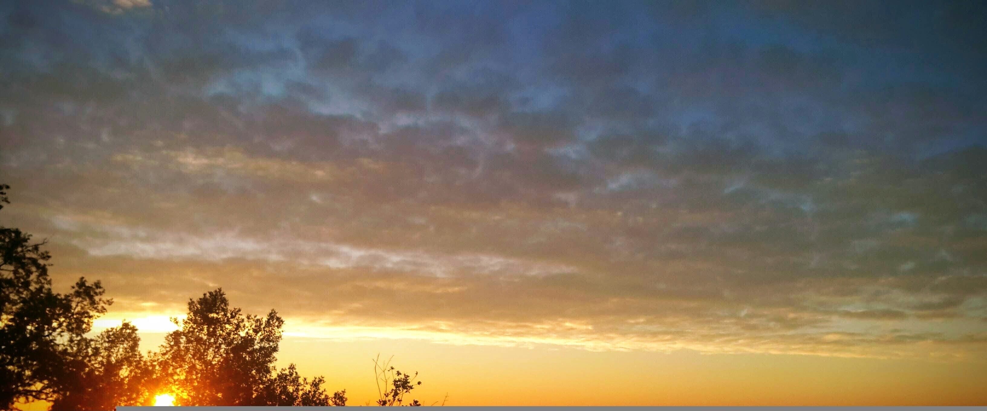 A sunset with clouds and trees.